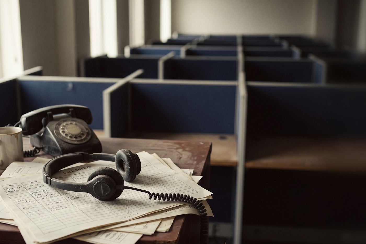 An abandoned call center desk with a headset and a rotary phone